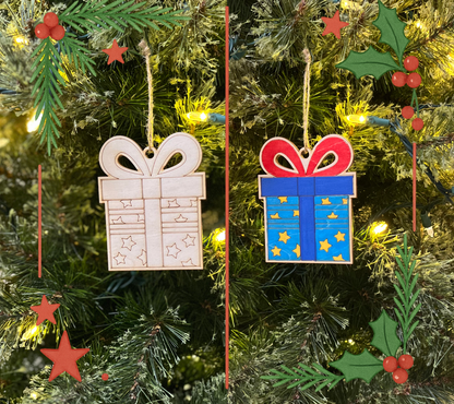 Two Christmas tree ornaments shaped like presents hanging on a decorated tree.