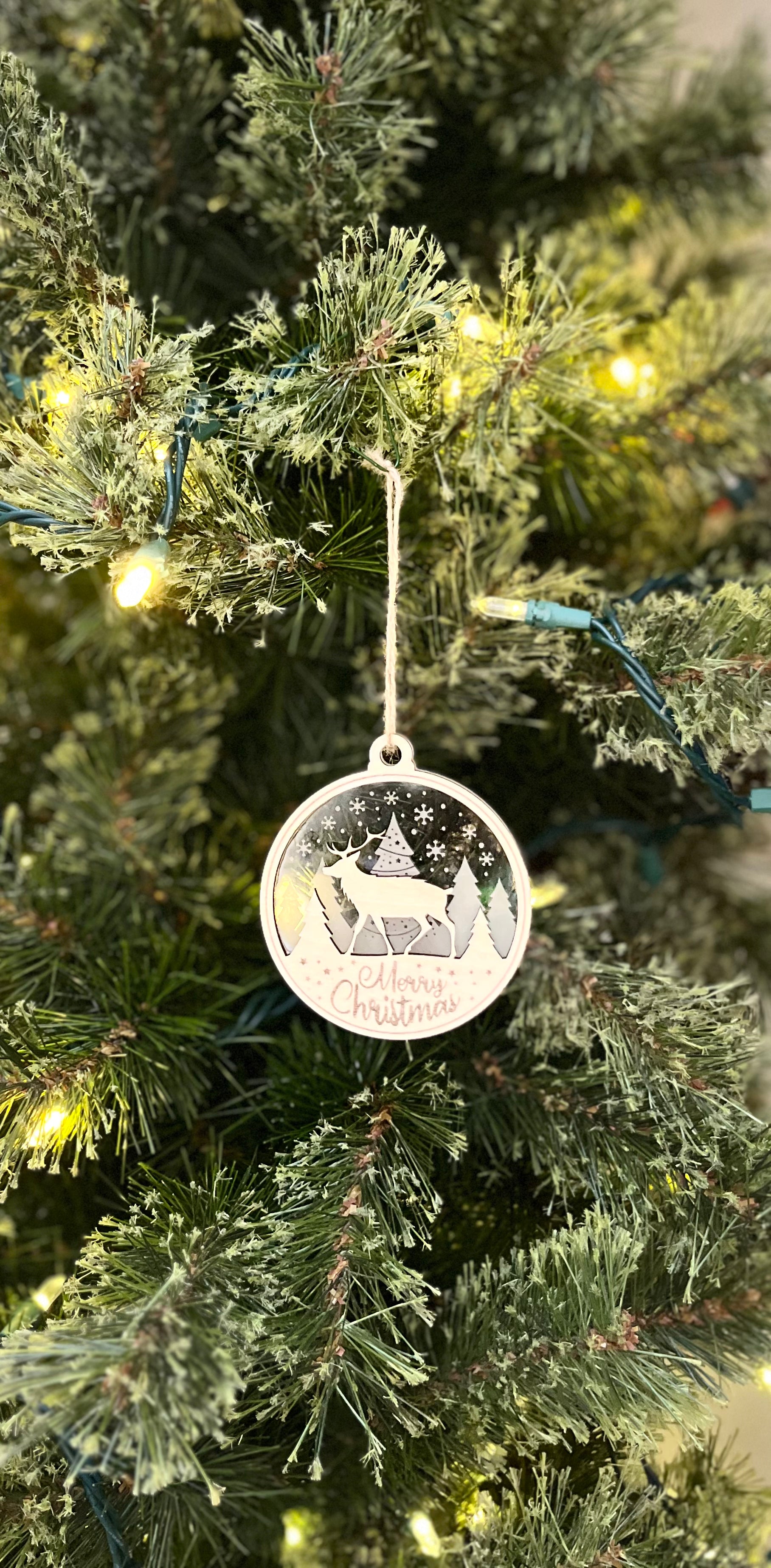 Decorative ornament on a Christmas tree with a reindeer design.