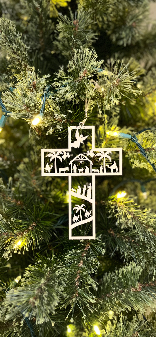 Decorative cross nativity ornament on a Christmas tree with lights