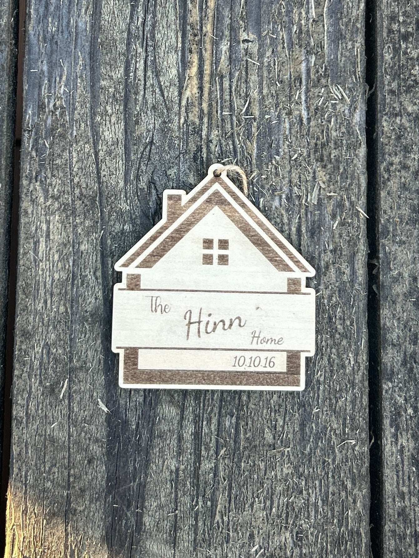 Small house-shaped sign with a name on a wooden surface