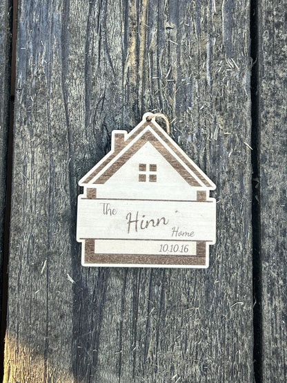 Small house-shaped sign with a name on a wooden surface