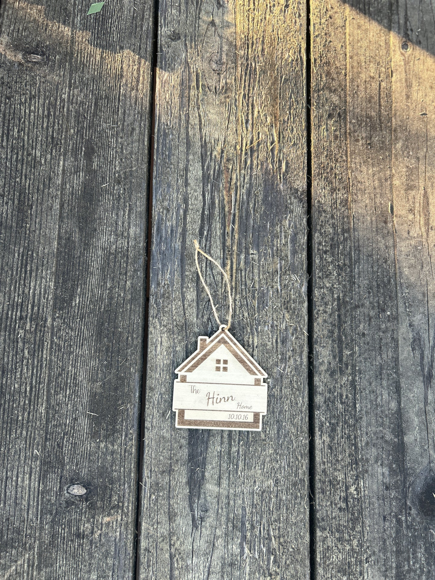 Small house-shaped ornament hanging on a wooden surface