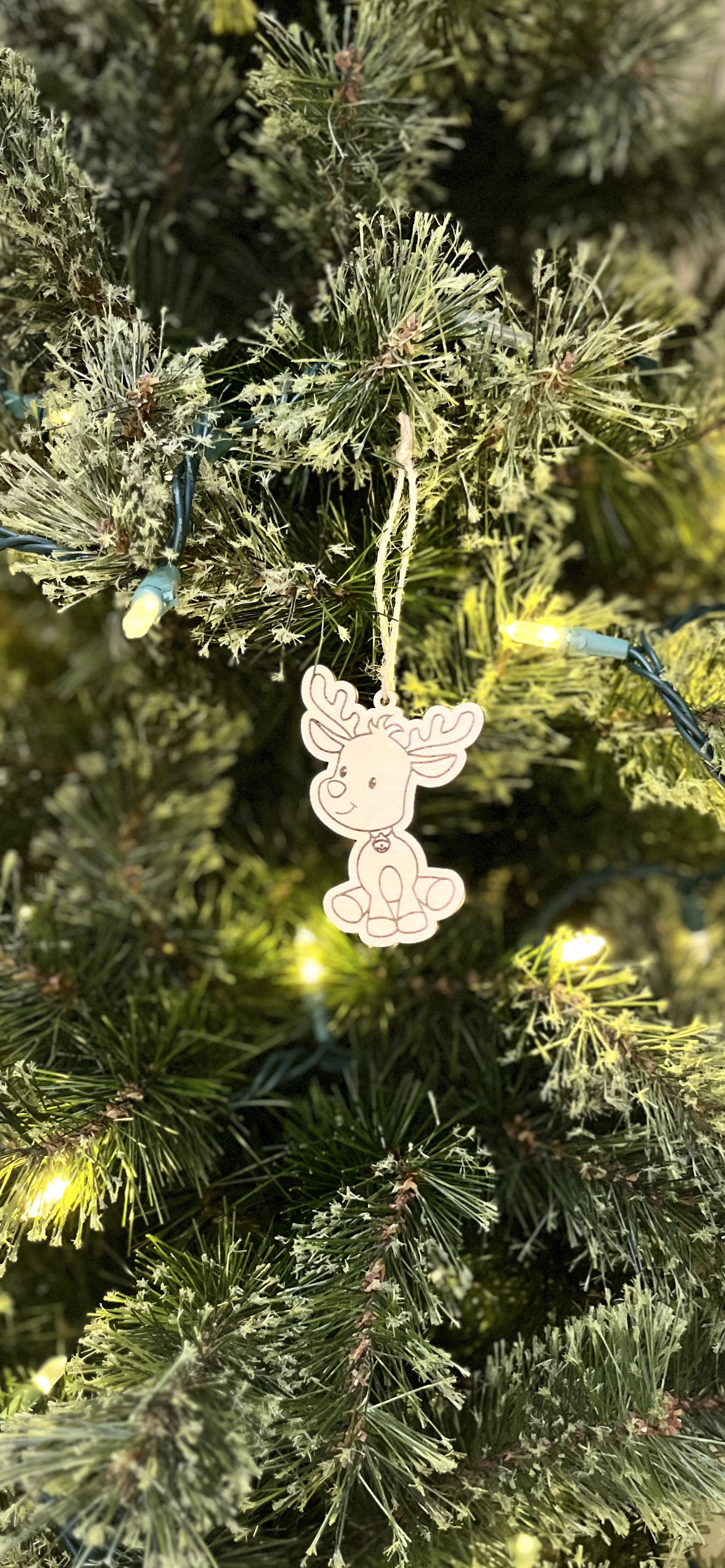 Decorative reindeer ornament on a Christmas tree with lights.